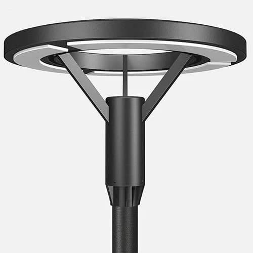 Circular disc-form post-top area luminaire — broad flat housing, translucent diffuser ring, central three-strut connector — on a black column, light background