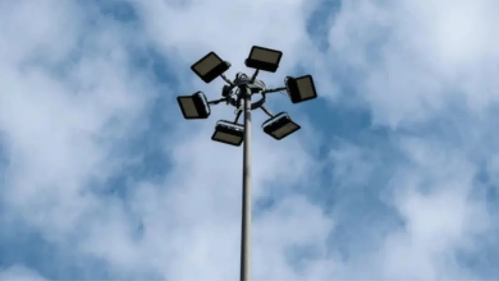 High-mast lighting head carrying six floodlights, viewed from below against cloud