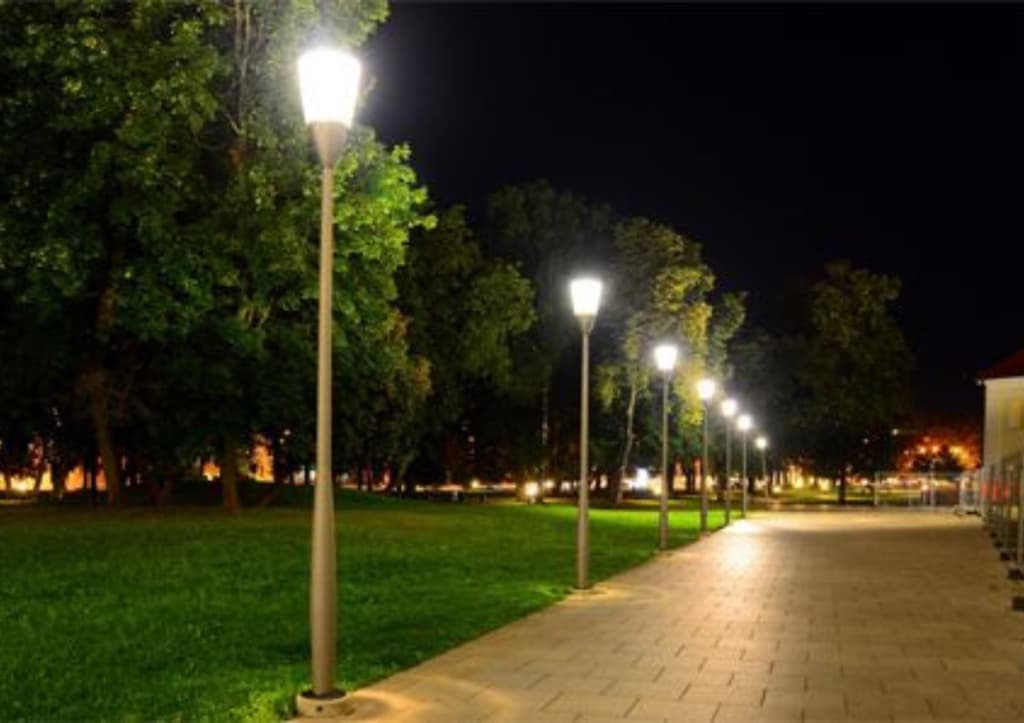 Post-top area lights lining a paved park walkway at night