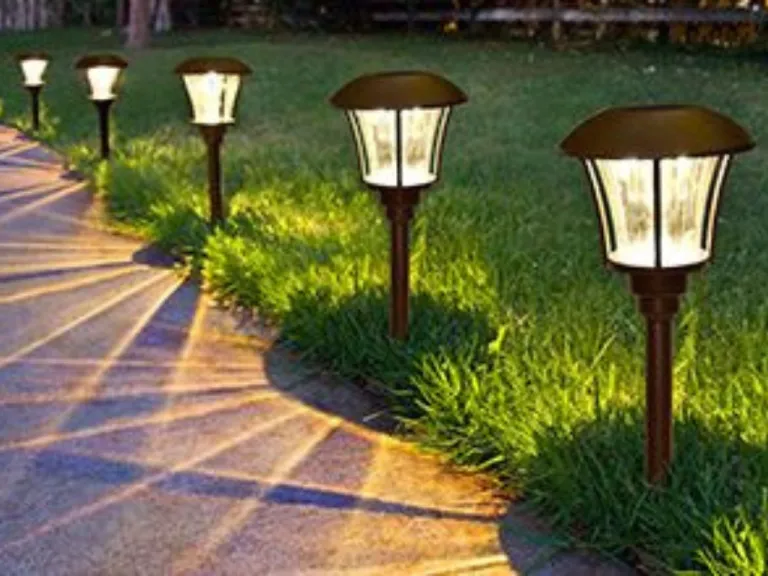 Line of low path lanterns edging a garden walkway at golden hour