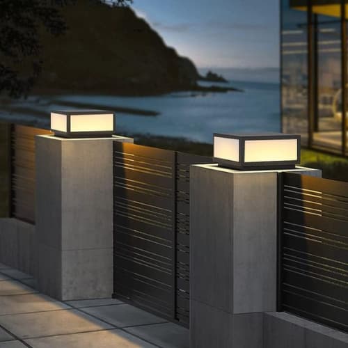 Square pillar-cap luminaires on concrete gate posts overlooking the coast at dusk