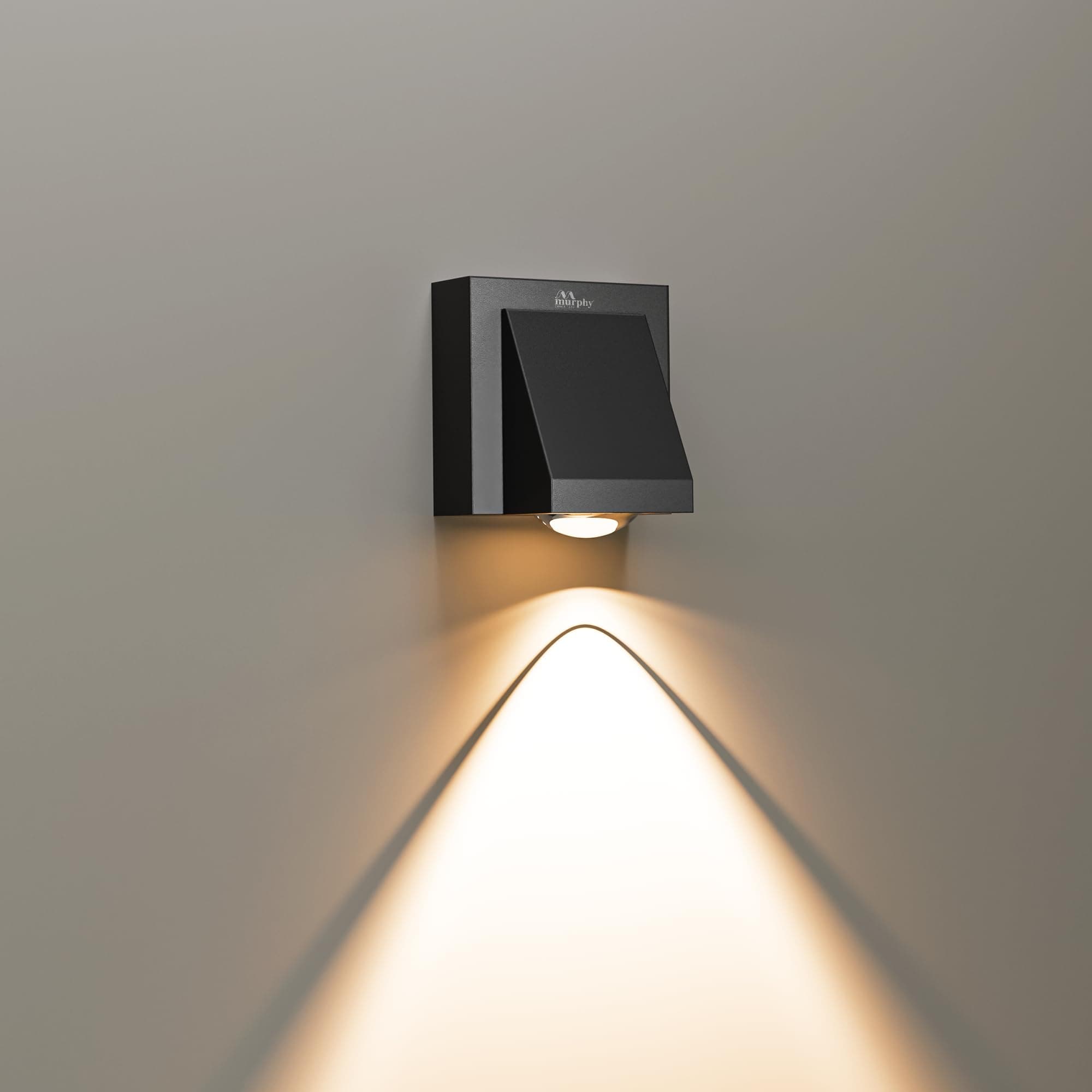 Black square wall-mounted wedge step light casting a warm scalloped triangular beam down a grey wall