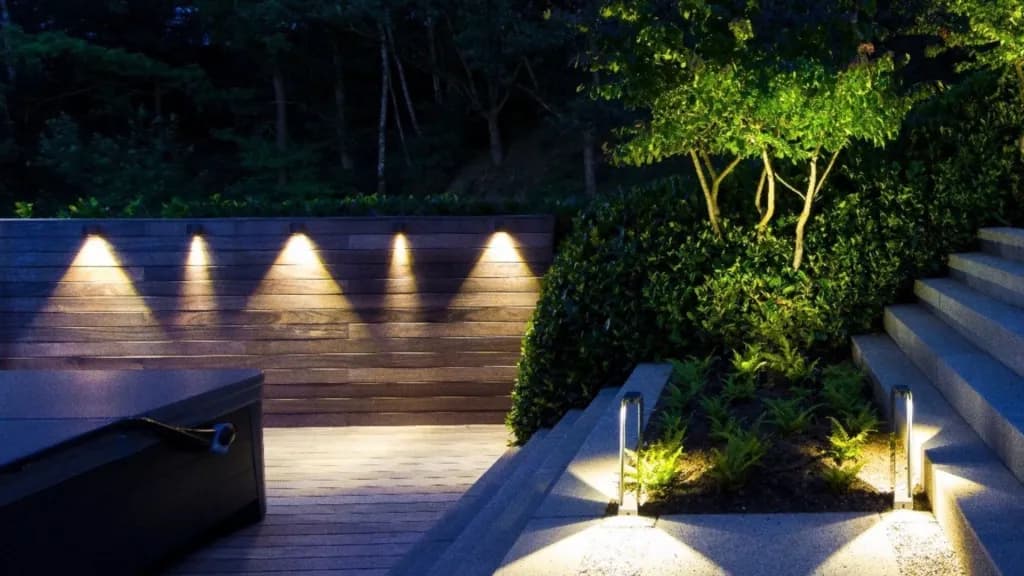 Warm downlights scalloping a timber garden wall beside planted steps at dusk